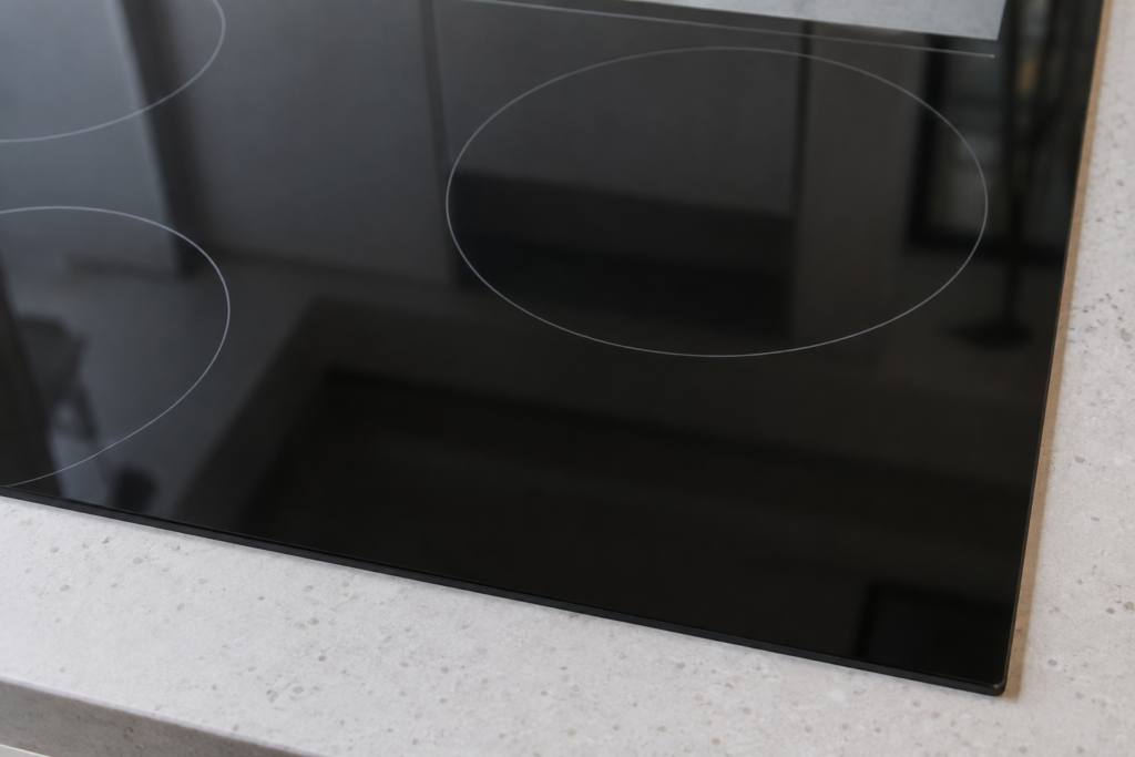 Close-up of an induction cooktop's control panel area with all indicator lights off.